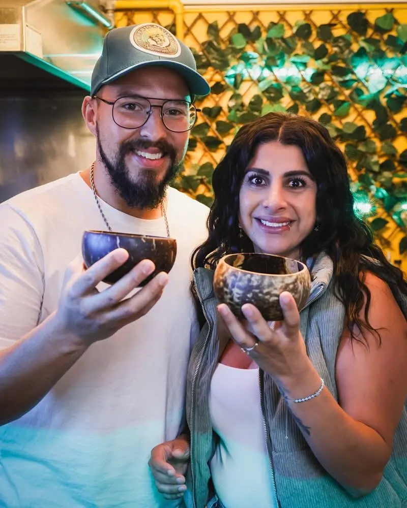 Carolina and Caio raising coconut shells of kava