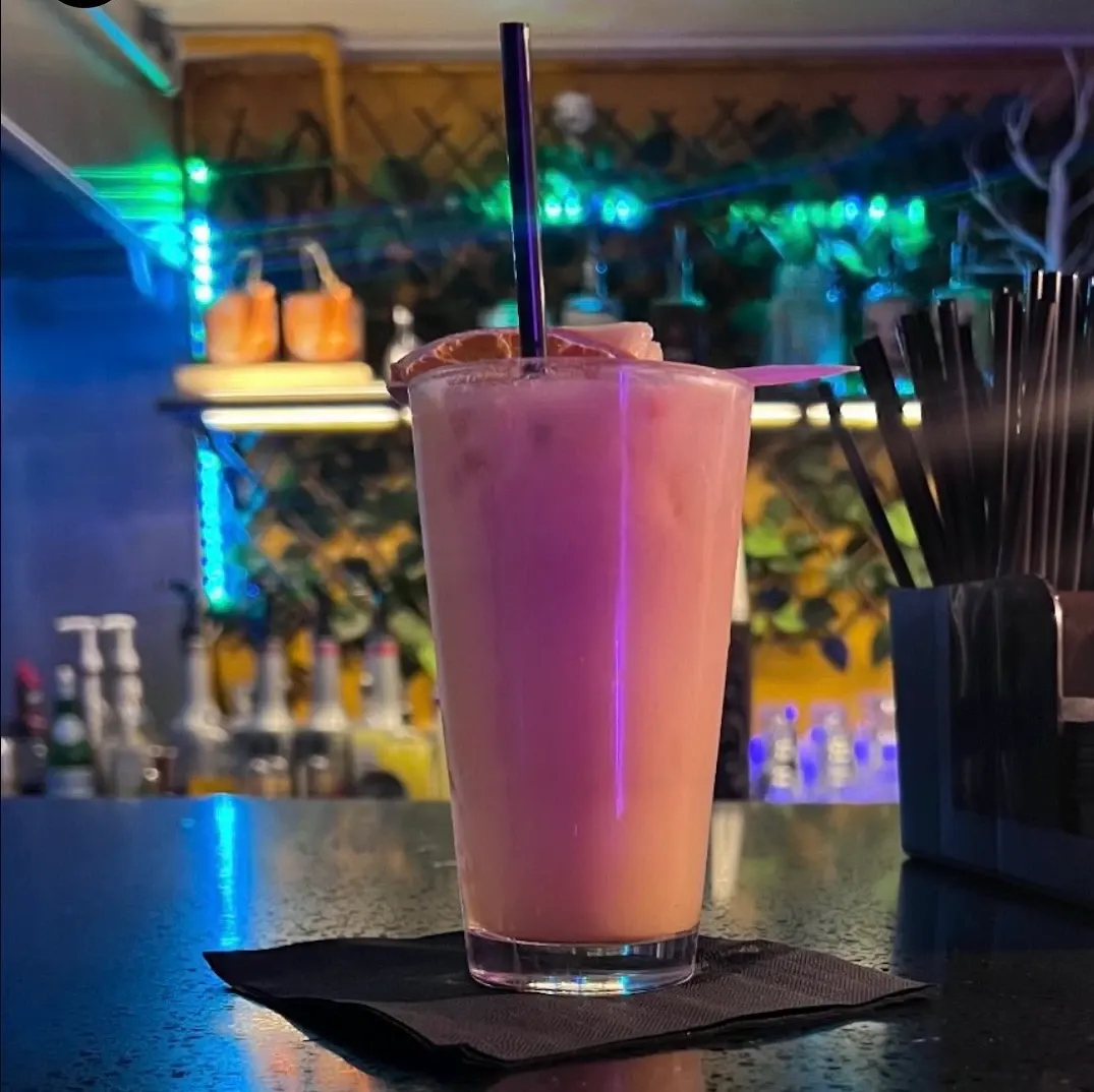 A creamy pink kavatail on the bar under green lights